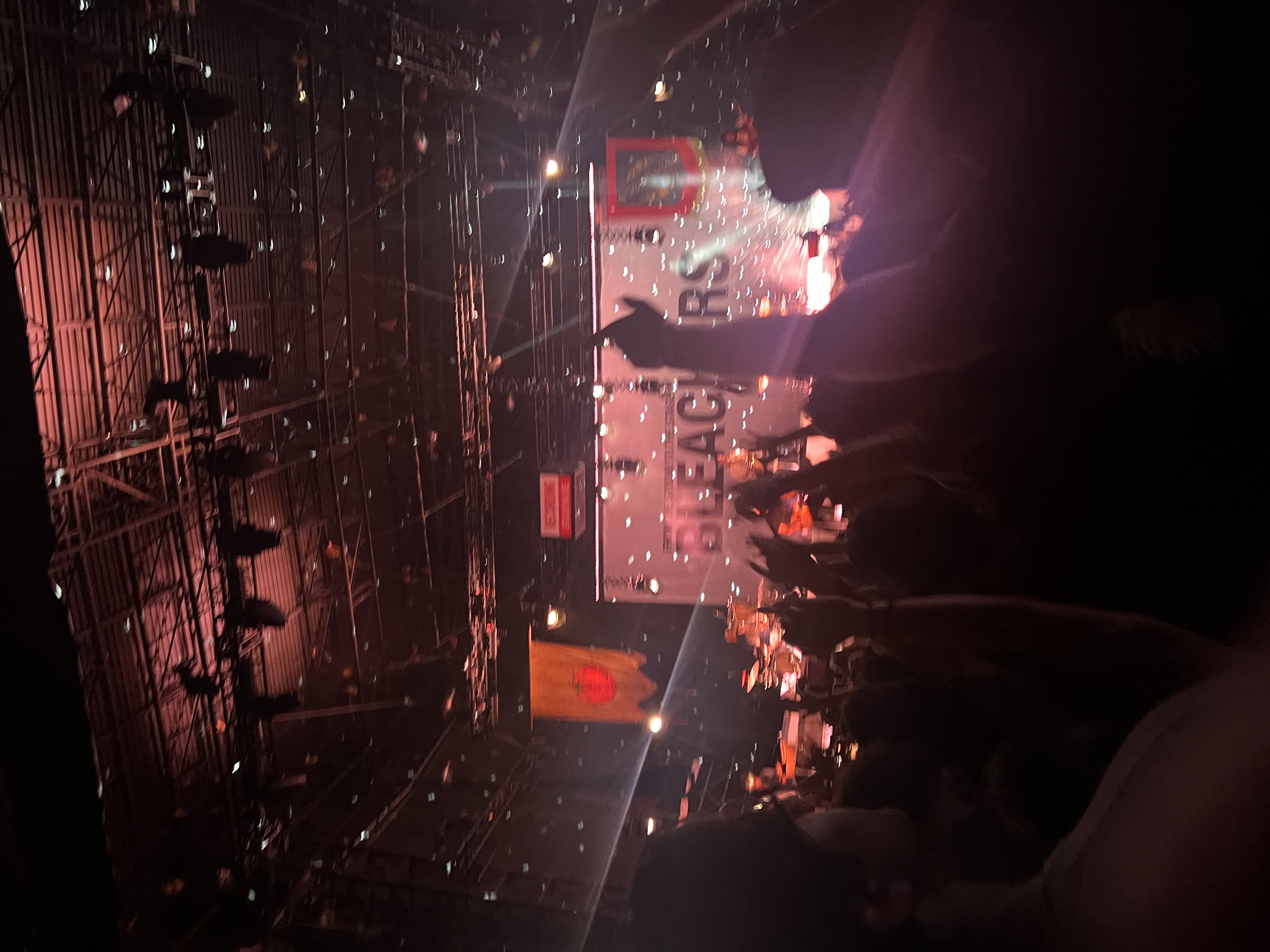 Wide view of the Bleachers concert from the crowd, stage lights and the band's banner visible.